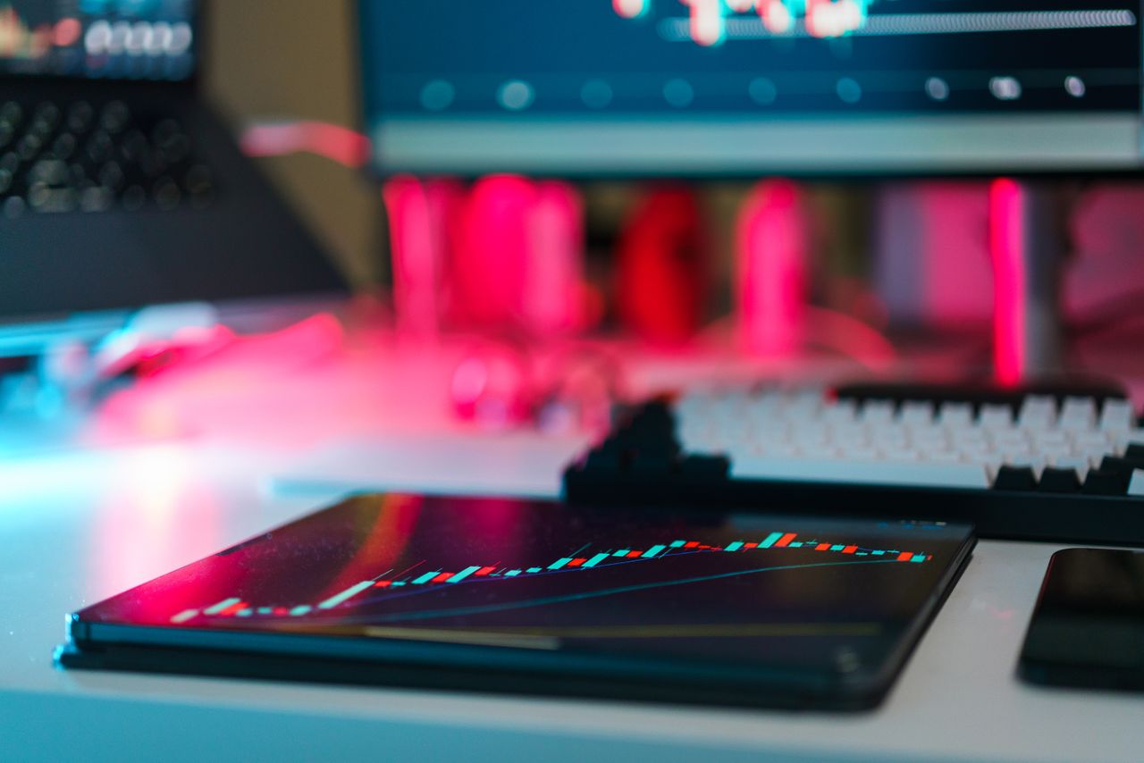 Installation de trading high-tech avec graphiques sur tablette et écrans d’ordinateur, illustrant l’analyse de données et les tendances financières.